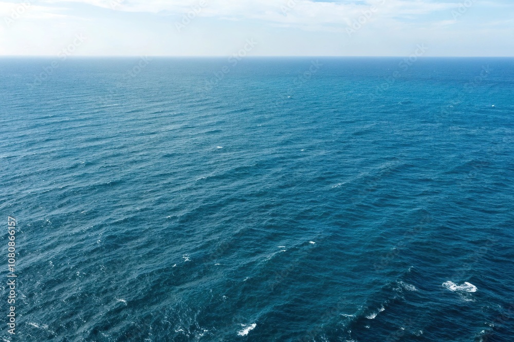 Aerial view of vast blue ocean with ripples and waves in the distance, deep sea, blue hues, ocean waves, turquoise water, natural wonder Aerial view of vast blue ocean with ripples and waves in the distance, deep sea, blue hues, ocean waves, turquoise water, natural wonder