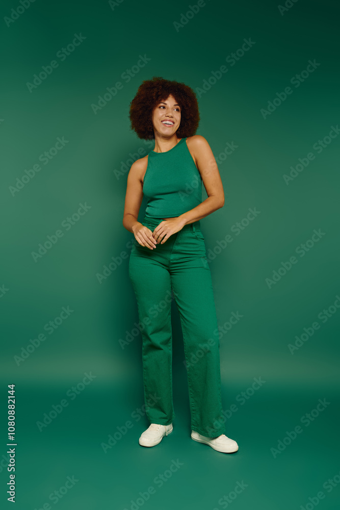 A young African American woman with curly hair radiates joy while standing against a vibrant green background. A young African American woman with curly hair radiates joy while standing against a vibrant green background.