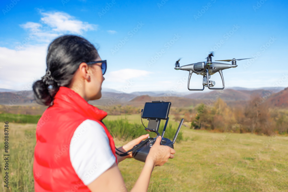 A young woman controls a drone with a remote control in her hands.