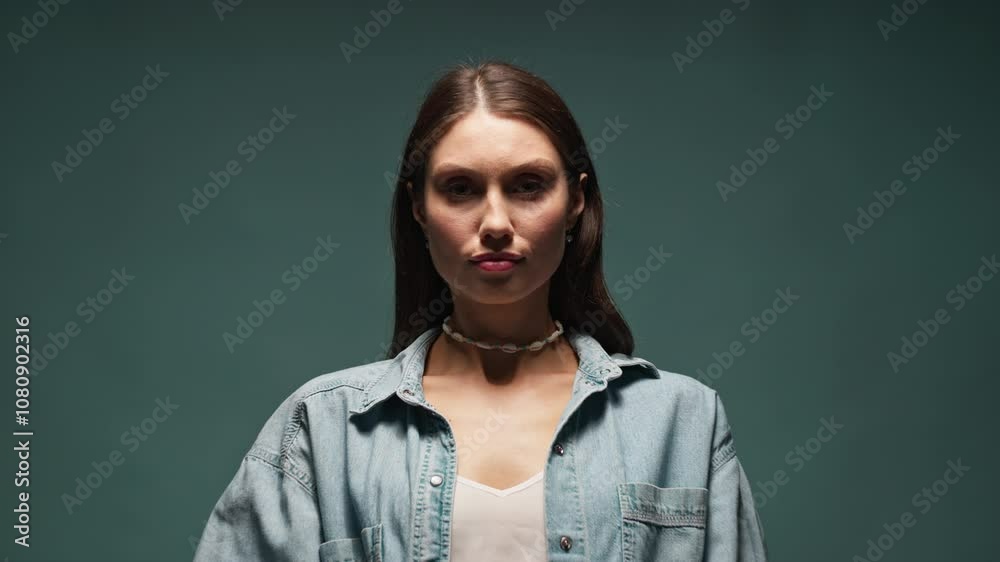 View on face portrait of beautiful woman look on camera serious on gray blue background. Light and shadow. Posing View on face portrait of beautiful woman look on camera serious on gray blue background. Light and shadow. Posing
