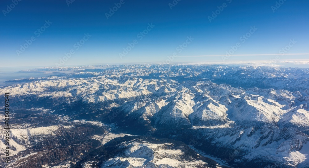 Obraz premium Aerial view of -capped mountains clear blue skies