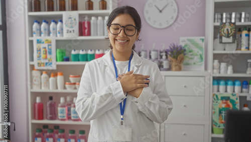 A young attractive hispanic brunette woman in a white coat smiling in a pharmacy store interior with shelves filled with various medical products and bottles. photo