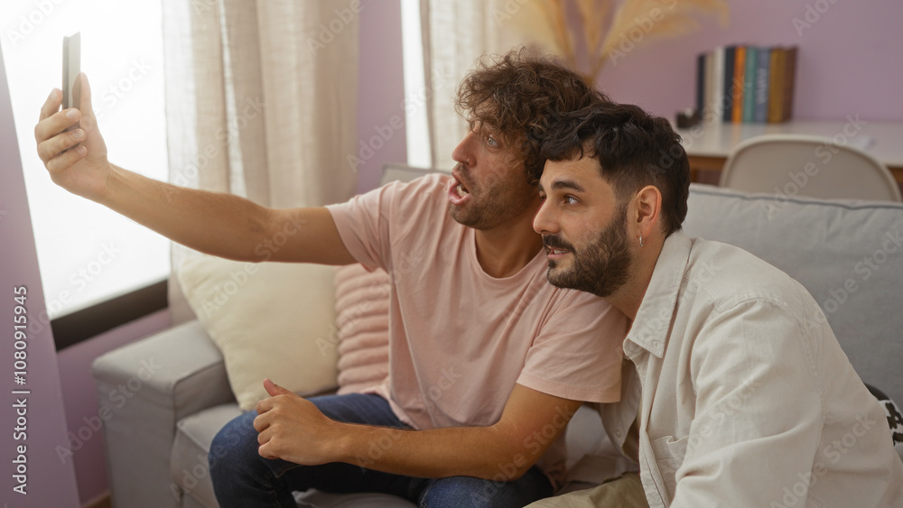 Obraz premium Men sitting together on a couch in a living room, taking a selfie with a smartphone and enjoying their time indoors, showcasing friendship and family bonds in a cozy apartment setting