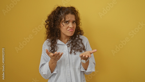 Bild auf Leinwand Young woman with curly brunette hair expressing confusion against a bright yello
