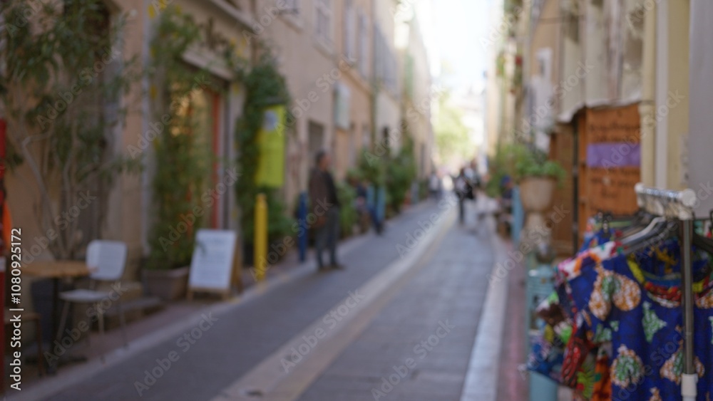 Blurred street scene in marseilles with out-of-focus man, colorful fabrics, outdoor setting, and european architecture, capturing lively french atmosphere with soft bokeh defocus. Blurred street scene in marseilles with out-of-focus man, colorful fabrics, outdoor setting, and european architecture, capturing lively french atmosphere with soft bokeh defocus.