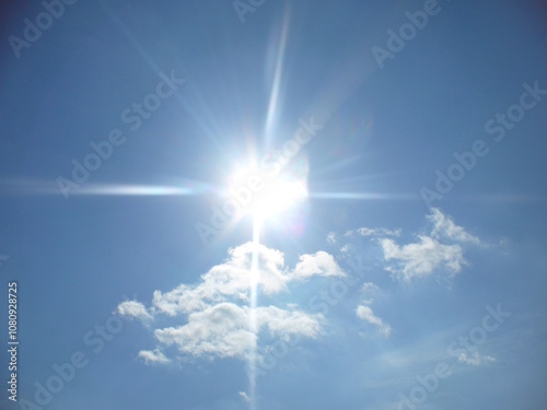 Sunny blue sky with sun rays and decorative white clouds - natural background. Topics: weather, meteorology, sun energy, season, beauty of nature, air space