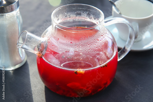 Red hot fruit tea brewed in a glass teapot