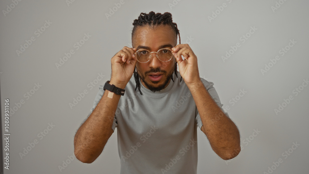 Young man with braids adjusting glasses over isolated white background, showcasing a modern style and confident expression. Young man with braids adjusting glasses over isolated white background, showcasing a modern style and confident expression.