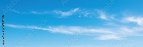 A tranquil blue sky with a few wispy stratus clouds stretching across the horizon, muted, sunny, calming