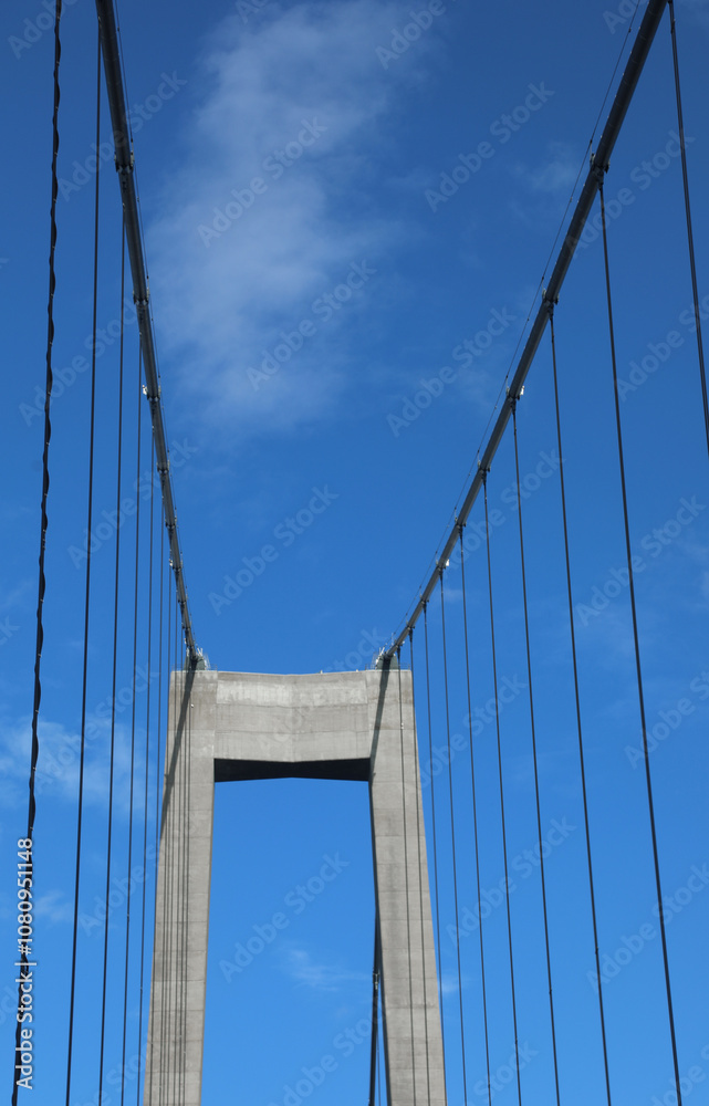reinforced concrete pillar of the suspension bridge with the robust steel cable stays and the blue sky reinforced concrete pillar of the suspension bridge with the robust steel cable stays and the blue sky
