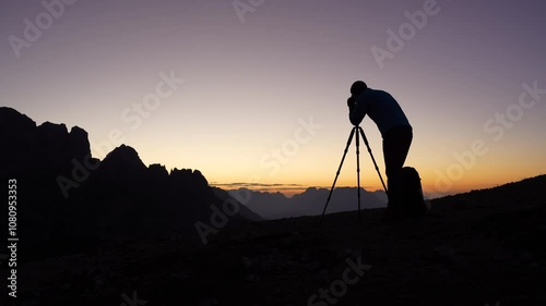 one man, photographer taking pictures alone in the mountains in the evening with colorful sky waiting for the night to come


