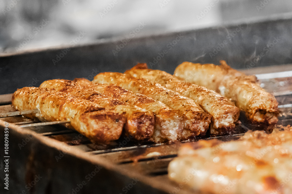 Close-up of grilled sausages sizzling on barbecue showcasing the charred and golden texture of the meat as it cooks over the fire Close-up of grilled sausages sizzling on barbecue showcasing the charred and golden texture of the meat as it cooks over the fire