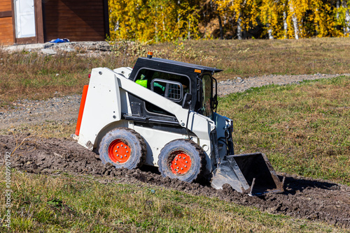 White mini loader working in rural area