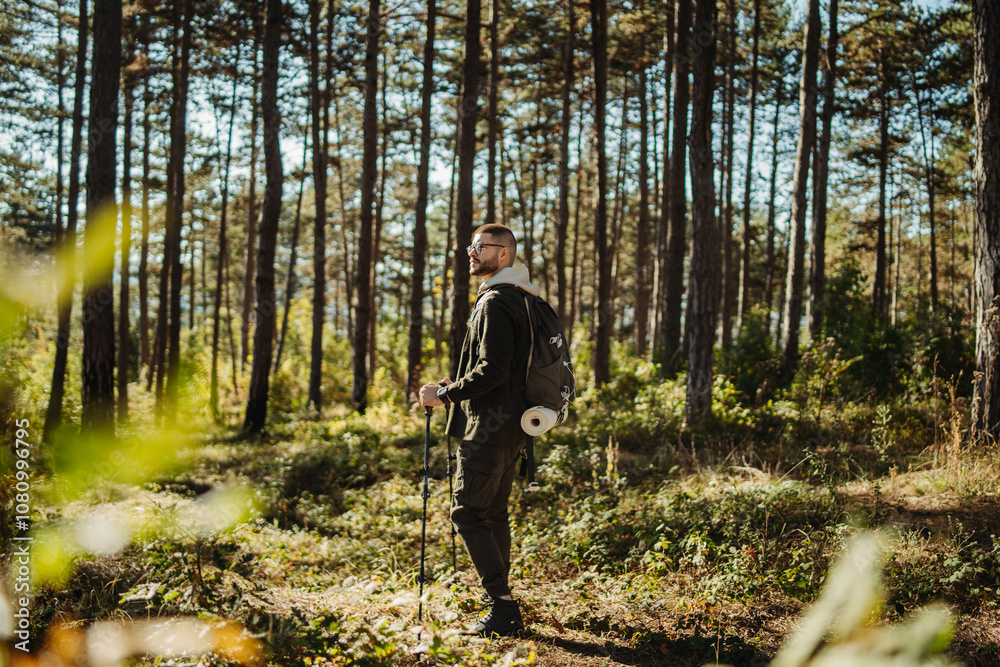 Obraz premium Young caucasian man hiking or trekking through the forest 