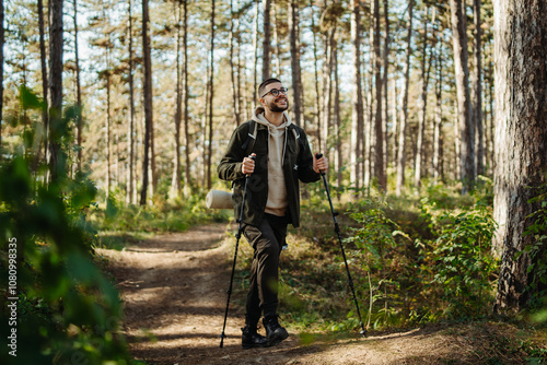 Young caucasian man hiking or trekking through the forest 