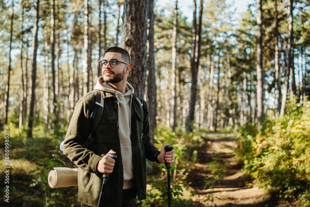 Young caucasian man hiking or trekking through the forest Young caucasian man hiking or trekking through the forest