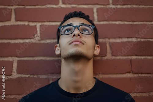 Young man in glasses looking up thoughtfully, with space for advertising messages around him