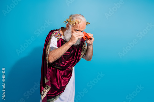 Photo of ancient character hold binoculars enjoy performance antique history look down isolated on blue color background photo