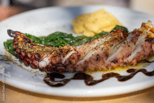 Traditional greek cuisine, grilled octopus sprinkled with herbs, with additions, dish on a plate in a restaurant, Greece