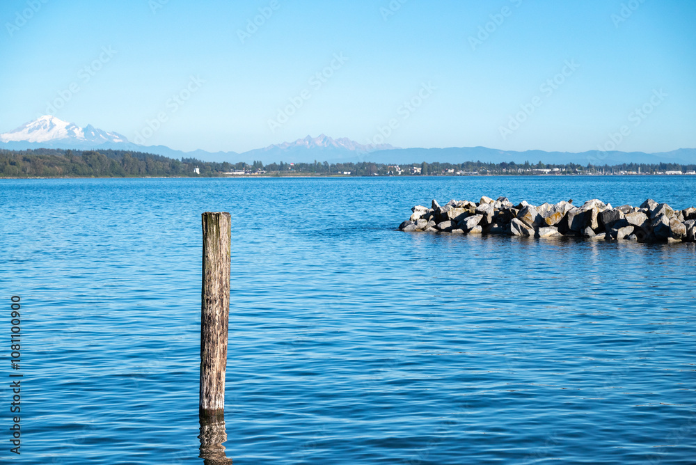 The blue sea, mountains in the background, and breakwater of White Rock, Canada The blue sea, mountains in the background, and breakwater of White Rock, Canada