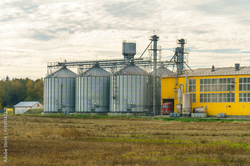 silver silos on agro manufacturing plant for processing drying cleaning and storage of agricultural products, flour, cereals and grain. Large iron barrels of grain. Granary elevator silver silos on agro manufacturing plant for processing drying cleaning and storage of agricultural products, flour, cereals and grain. Large iron barrels of grain. Granary elevator