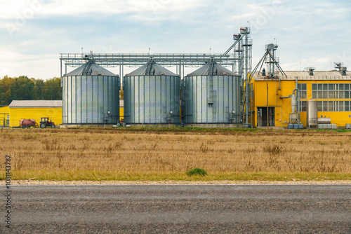 silver silos on agro manufacturing plant for processing drying cleaning and storage of agricultural products, flour, cereals and grain. Large iron barrels of grain. Granary elevator