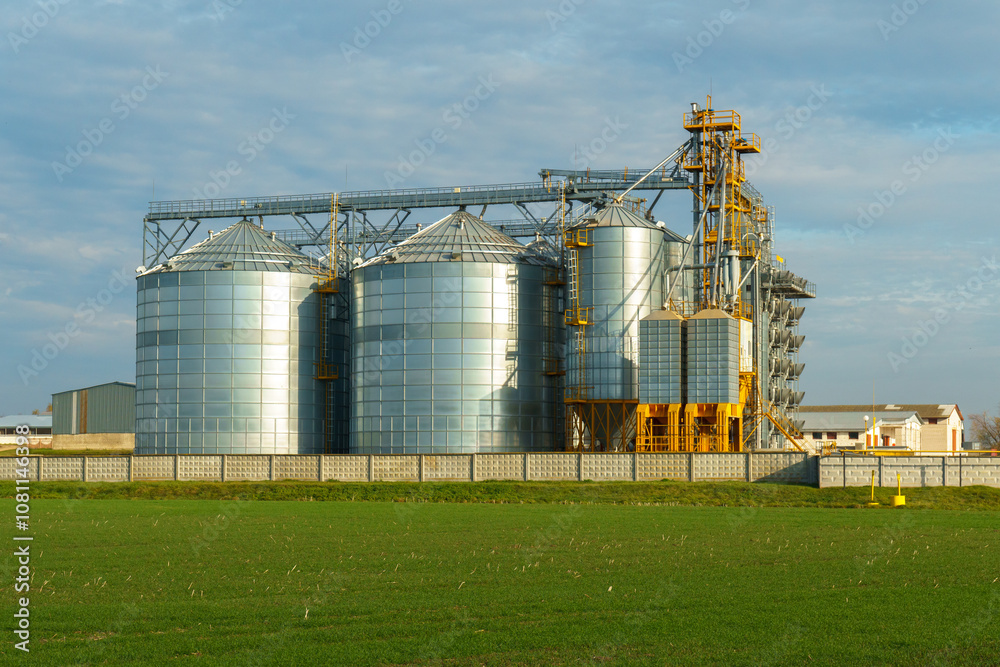 silver silos on agro manufacturing plant for processing drying cleaning and storage of agricultural products, flour, cereals and grain. Large iron barrels of grain. Granary elevator silver silos on agro manufacturing plant for processing drying cleaning and storage of agricultural products, flour, cereals and grain. Large iron barrels of grain. Granary elevator