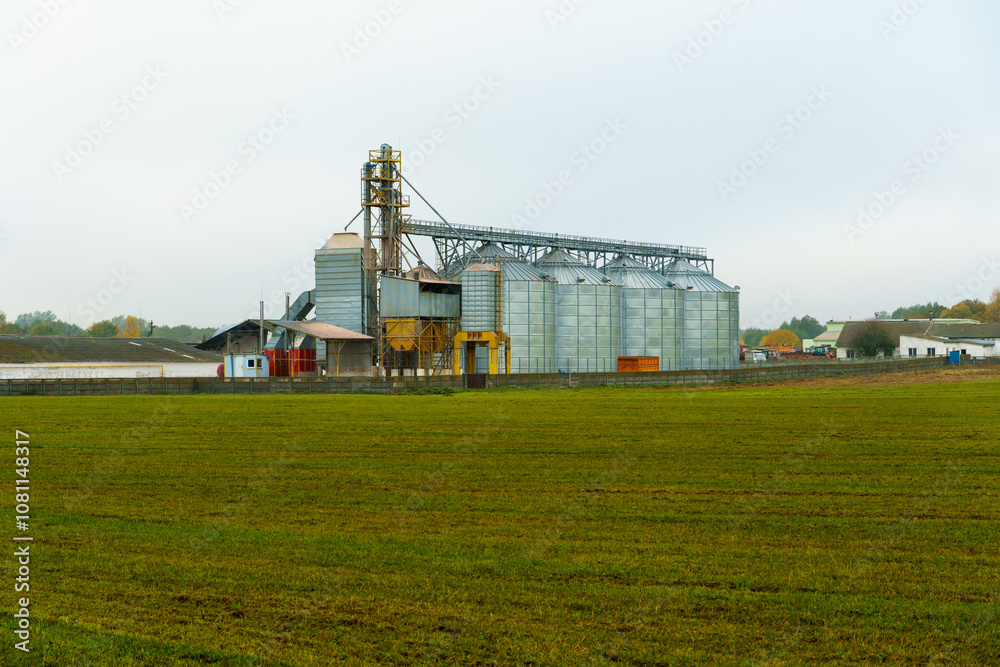 silver silos on agro manufacturing plant for processing drying cleaning and storage of agricultural products, flour, cereals and grain. Large iron barrels of grain. Granary elevator silver silos on agro manufacturing plant for processing drying cleaning and storage of agricultural products, flour, cereals and grain. Large iron barrels of grain. Granary elevator
