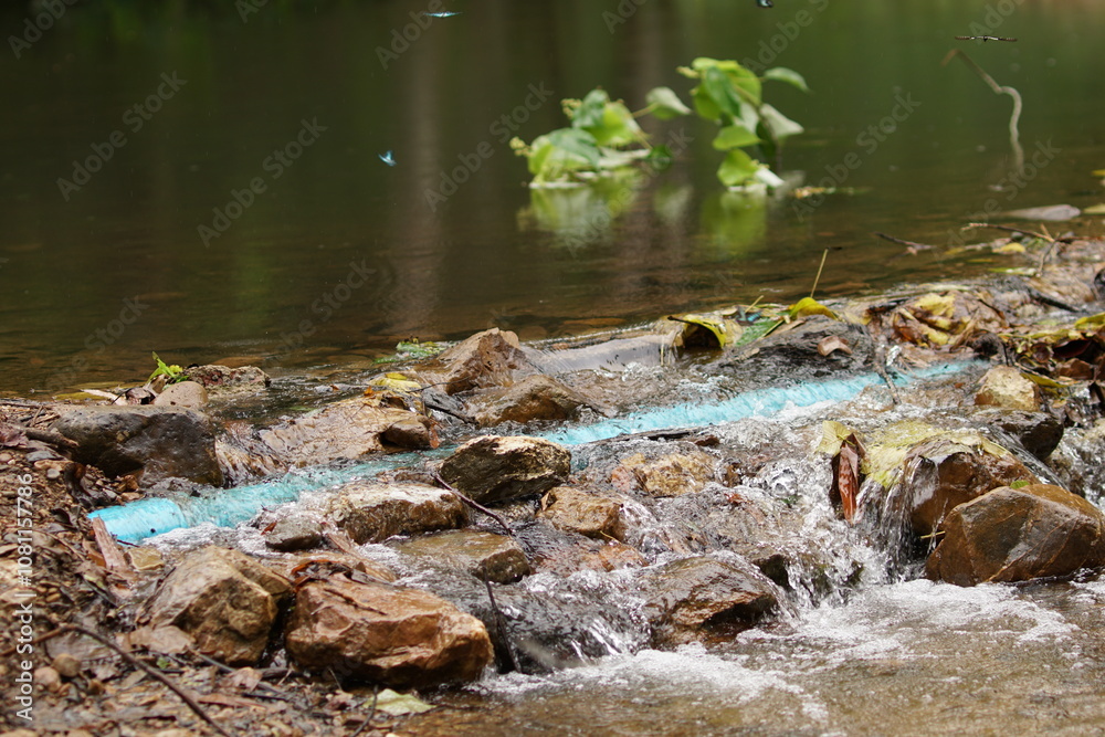 Fototapeta premium small waterfall flow over the river in Thailand with blue pipeline