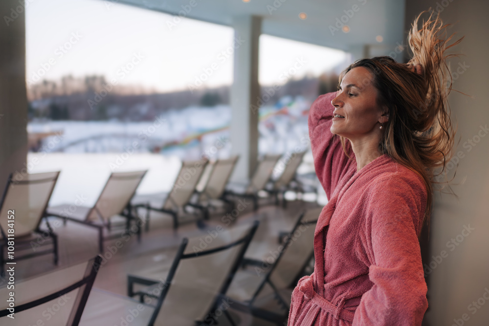 Woman Throws Back her Hair and Dries it, while Enjoying a Spa Break by the Window Woman Throws Back her Hair and Dries it, while Enjoying a Spa Break by the Window