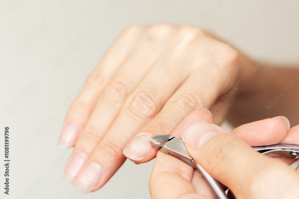 A young Caucasian woman doing an edged manicure for herself with the help of nail clippers for cuticles. Hand care A young Caucasian woman doing an edged manicure for herself with the help of nail clippers for cuticles. Hand care