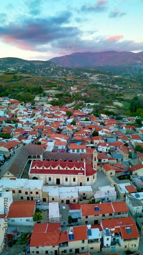 Vertical mobile reel scenic drone view of the city of Omodos and Holy Cross monastery (Timios Stavros), Cyprus, with red sunset photo