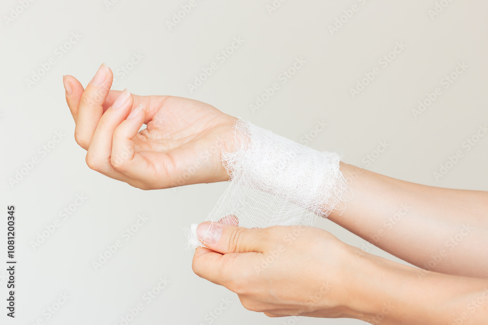 A young Caucasian woman in beige underwear injured herself and bandaged her hand. First aid at home.