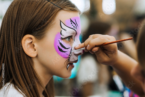 Professional artist paints on the face, does aqua make-up, make-up for a girl at a children's party. Photography, portrait.