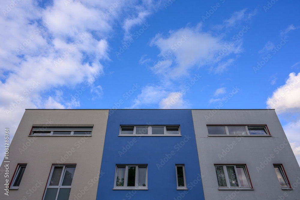 Apartment block with blue centre stripe and blue sky with clouds Apartment block with blue centre stripe and blue sky with clouds