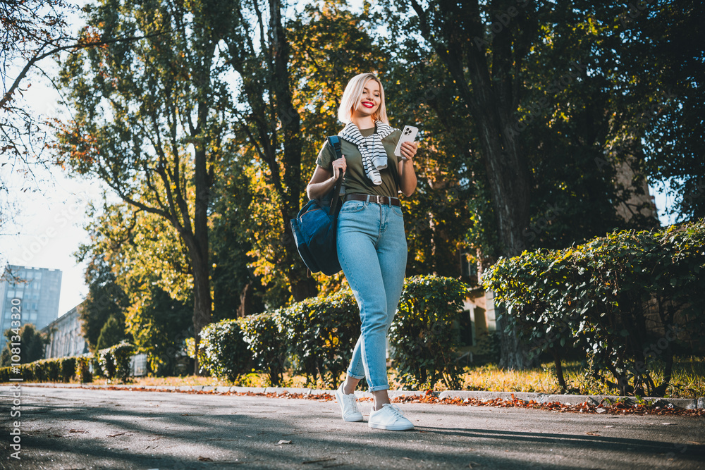 Full size photo of positive young blonde girl wear khaki outfit tied shoulders sweater walk hold device park sunny spring weather outside Full size photo of positive young blonde girl wear khaki outfit tied shoulders sweater walk hold device park sunny spring weather outside