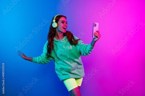 Photo of charming positive woman wear green sweatshirt headphones tacking selfie modern device isolated neon blue color background photo