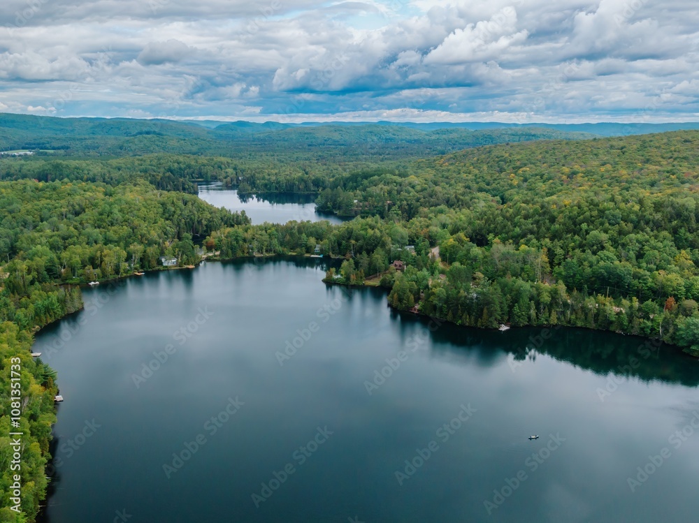 A canoe on a calm tranquil lake with a forest in the horizon. Lac Lambert, Saint-Alexis-des-Monts, Quebec, Canada. A canoe on a calm tranquil lake with a forest in the horizon. Lac Lambert, Saint-Alexis-des-Monts, Quebec, Canada.