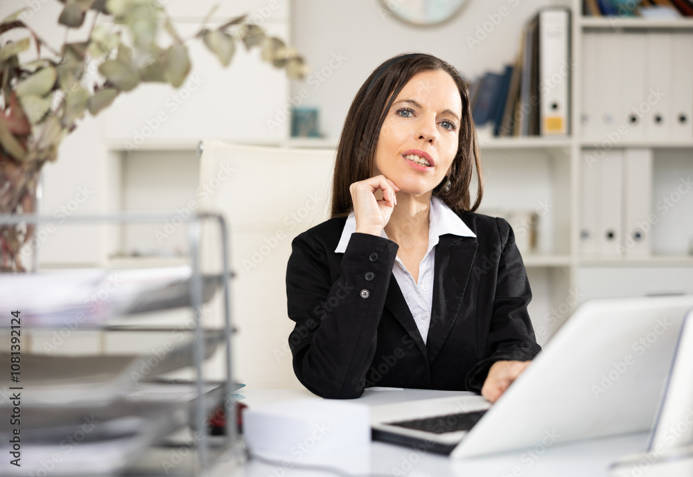 Woman accountant sitting at her working table in office and looking at camera. Woman accountant sitting at her working table in office and looking at camera.