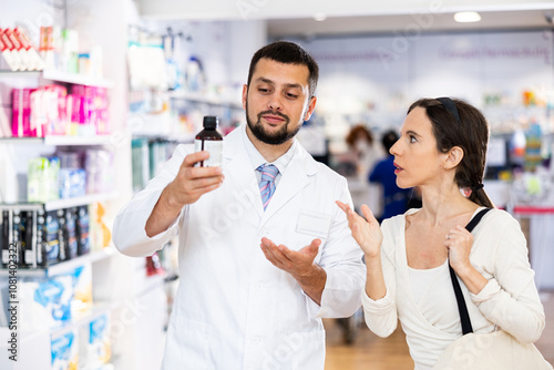 Friendly man pharmacist helping young adult woman choosing medical supplies at drugstore