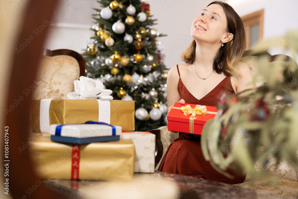 Young woman, being in anticipation of the holiday, prepares Christmas presents for guests at home Young woman, being in anticipation of the holiday, prepares Christmas presents for guests at home