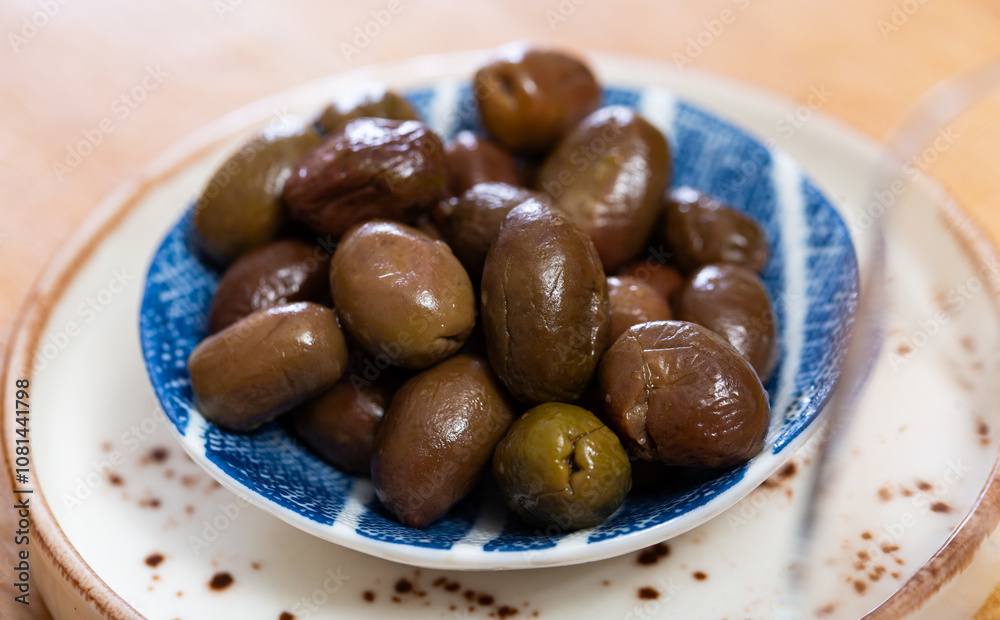 Large green olives with pits served to table in bowl