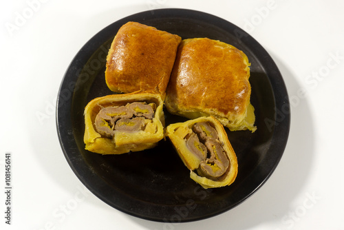 Bolen Pisang is a light dish made from bananas covered in rolled sheets of pastry dough. Various toppings such as cheese and chocolate. Served in black plate on white background. Selective focus image photo