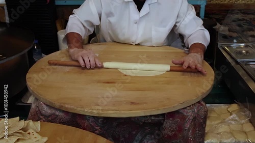 slow motion process of making gozleme - Turkish national flatbread. A woman rolls out the dough by hand with a rolling pin