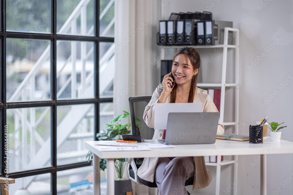 Attractive and professional millennial business Asian woman freelancer making telephone call share good news about project working in office workplace, business finance concept.