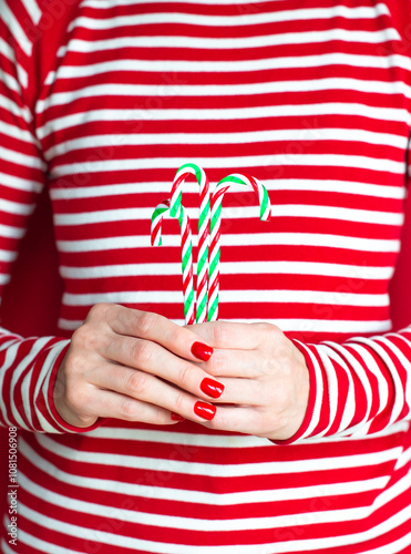 Hands of white woman with red manicure holding Christmas candy canes 
 photo