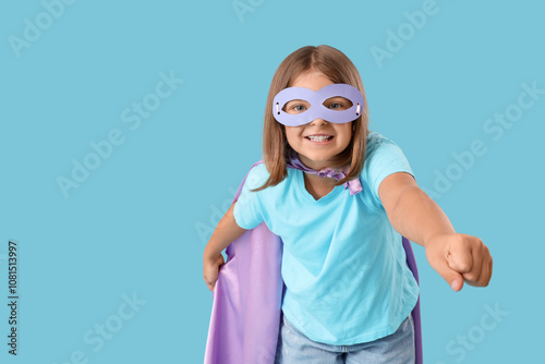 Teenage girl dressed as superhero on blue background