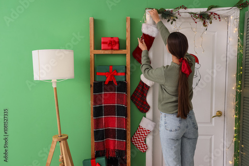 Young woman decorating door...