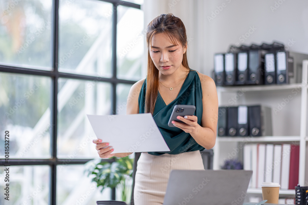 asian business woman working in office checking documents and phone . young businesswoman accounting manager executive or lawyer using laptop reading paper file financial report, tax invoice. asian business woman working in office checking documents and phone . young businesswoman accounting manager executive or lawyer using laptop reading paper file financial report, tax invoice.