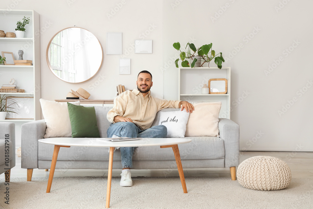 Young man sitting on comfortable sofa at home Young man sitting on comfortable sofa at home